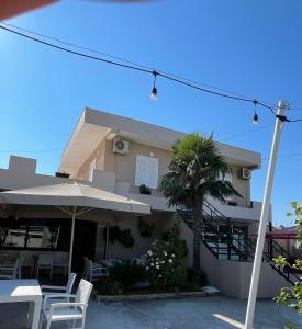 a house with chairs and an umbrella and a palm tree at Lea home in Vlorë +7 photos