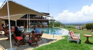 a group of people sitting at a table by a pool at Mwanzo Lodge in Naivasha