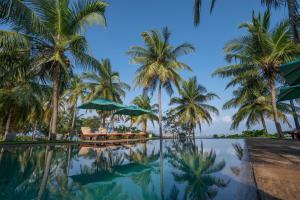 a pool with palm trees and chairs and umbrellas at Villa Sethawadi Hotel and Kitesurf Centre in Kalpitiya