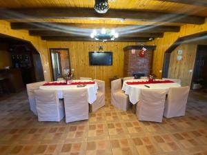 a room with two tables and white chairs and a television at Pensiunea Ana in Ceahlău