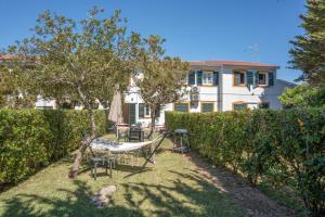 a garden with a table and chairs and a building at Villa Noa in Cala en Bosc