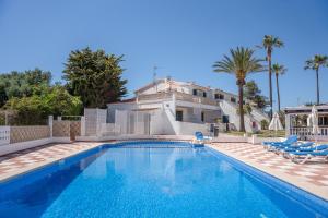 a swimming pool with chairs and a house at Villa Noa in Cala en Bosc
