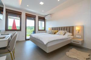 a bedroom with a bed and a desk and windows at Apartments Villa Ana in Palit