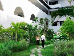 a man and a woman walking through a garden at Kiara Beachtown Nusa Dua in Nusa Dua