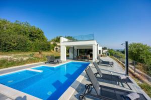 a swimming pool with chairs and a house at Villa Nono in Motovun