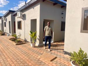 a man is standing outside of a house at Cadami apartments in Mazabuka