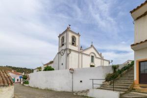 a small white church with a steeple and stairs at Casa Formosa in Odeceixe