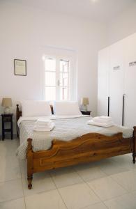 a white bedroom with a wooden bed with white pillows at Emporios 1930, Seafront stone house in Emporeiós