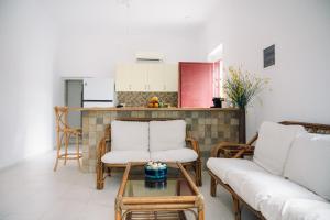 a living room with two white chairs and a table at Emporios 1930, Seafront stone house in Emporeiós