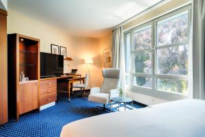 a hotel room with a bed and a desk and a tv at Welcome Parkhotel Bochum in Bochum