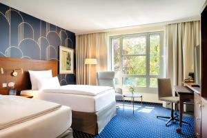 a hotel room with two beds and a desk at Welcome Parkhotel Bochum in Bochum +39 photos