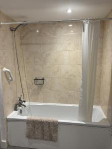 a bathroom with a bath tub with a shower curtain at The Flat The Plough in Birdbrook