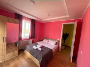 a pink bedroom with a bed with a pink wall at Paceri in Itʼkhvisi