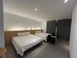 a hotel room with two beds and a chair at Rolling Pin Homestay in Tainan
