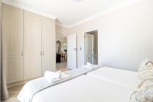 a white bedroom with a large bed with white cabinets at Winelands Golf Lodges 24 in Stellenbosch