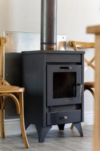 a black stove sitting in a room with chairs at Winelands Golf Lodges 24 in Stellenbosch