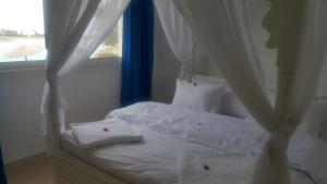 a bedroom with a bed with white sheets and a window at Twin Lagoon Apartment at White Villas El Gouna in Hurghada