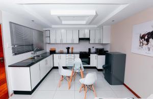 a kitchen with white cabinets and a black refrigerator at Goshen villas in Mbabane