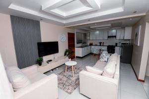 a living room with white furniture and a kitchen at Goshen villas in Mbabane +4 photos