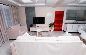 a living room with two white couches and a tv at Goshen villas in Mbabane