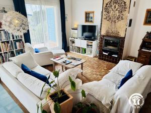 a living room with white couches and a tv at Entre mer et village in Leucate