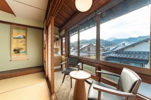 a room with chairs and a table and a large window at 湯宿ささくら in Kinosaki