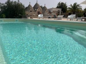 a swimming pool with blue water in front of a house at Trulli del boschetto in Putignano