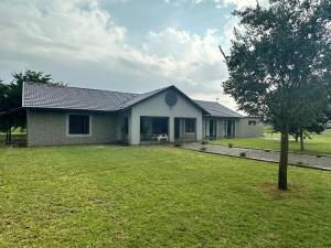 a white house with a tree in the yard at ValView Guest Lodge in Thabazimbi +8 photos