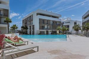 a woman laying in a hammock next to a swimming pool in a building at Casa Arena Rosa in Jávea
