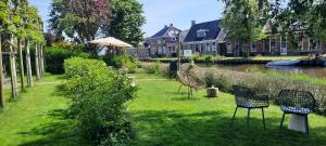 a group of chairs sitting in the grass next to a river at Noardlik B&B in Birdaard