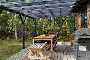 a wooden table and chairs on a patio with a grill at Nordic Nature Hideaway in Yderby +23 photos