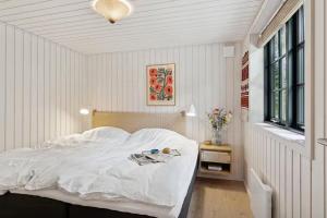 a bedroom with a bed with white sheets and a window at Nordic Nature Hideaway in Yderby