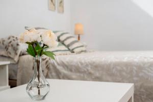 a vase of flowers on a table in a bedroom at Sol y breeze in Torre del Mar +16 photos