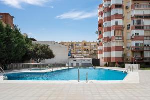 a swimming pool in front of a tall building at Sol y breeze in Torre del Mar