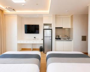 two beds in a small room with a kitchen at Gangneung Top Ocean in Gangneung