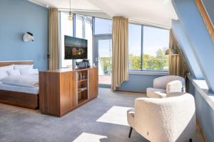 a bedroom with a bed and a tv and a chair at THE GRAND Ahrenshoop in Ahrenshoop