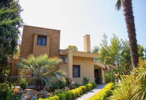 a house with palm trees in front of it at Azalea Villa, Anthology Villas in Sani, ex Sani Luxury Villas Collection in Sani Beach