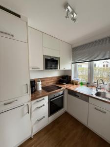 a white kitchen with wooden floors and white cabinets at Ferienhaus SPO 54 grad in Böhl