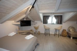 a room with a bed and a tv and chairs at Cosmopolitan Suites in Parga
