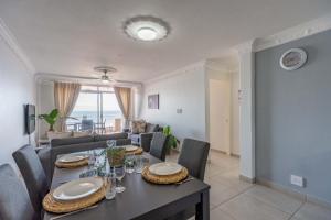 a dining room and living room with a table and chairs at Cozumel 216 in Umdloti