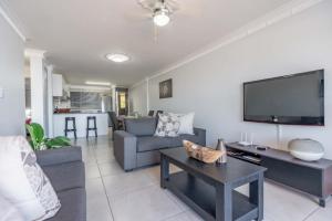 a living room with a couch and a tv at Cozumel 216 in Umdloti