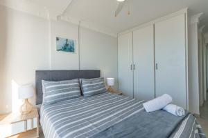a bedroom with a bed with blue and white stripes at Cozumel 216 in Umdloti +20 photos