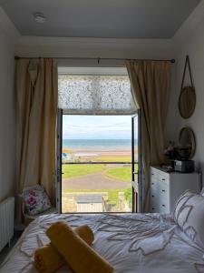 a teddy bear sitting on a bed in front of a window at Sea view Villa Holiday and Corporate Let Accommodation in Prestwick