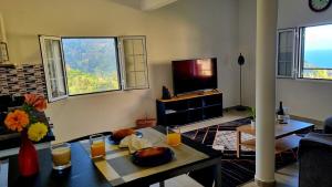 a living room with a table and a tv at Villa Borboleta in Santana