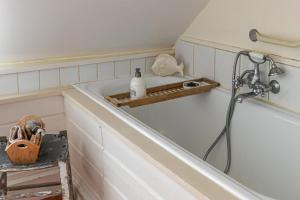 a bathroom with a bath tub with a shower and a shelf at Cottages Croix Abbé, Bergeronnette in Saint-Valéry-sur-Somme +12 photos