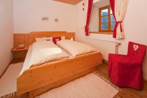 a bedroom with a wooden bed and a red chair at Hof Wieser in Patergassen