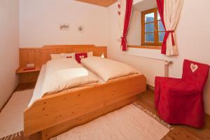 PatergassenにあるHof Wieserのベッドルーム1室(木製ベッド1台、赤い椅子付)