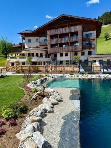 a house with a swimming pool in front of a building at Berghotel Alpenklang in Grossarl