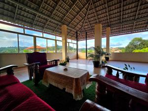 a living room with a table and chairs and windows at Nellakki Homestay in Madikeri