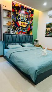 a bedroom with a blue bed with a painting on the wall at บ้านประภัสราคม โฮมสเตย์ นครสวรรค์ in Ban Ko Ta Thep